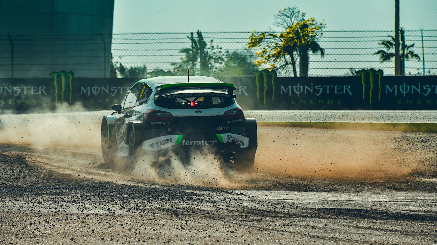 Rennwagen driftet auf einer staubigen Dirt-Strecke.